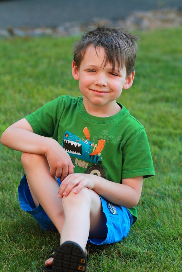 Smiling little boy sitting in the grass.