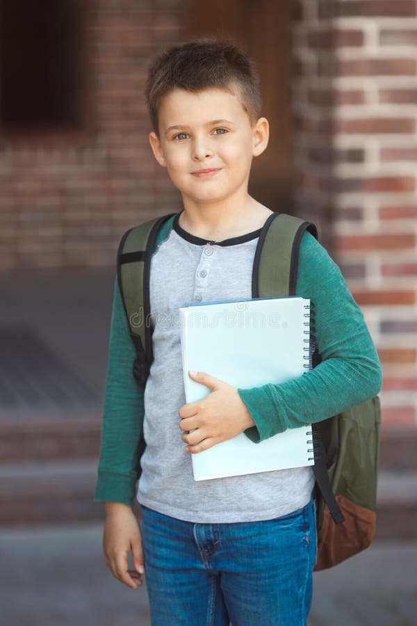 Smiling little boy 6-7 years old goes to school in casual clothes and backpack