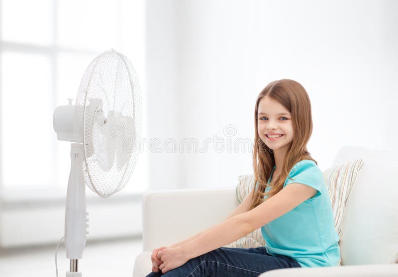 Smiling little girl with big fan at home