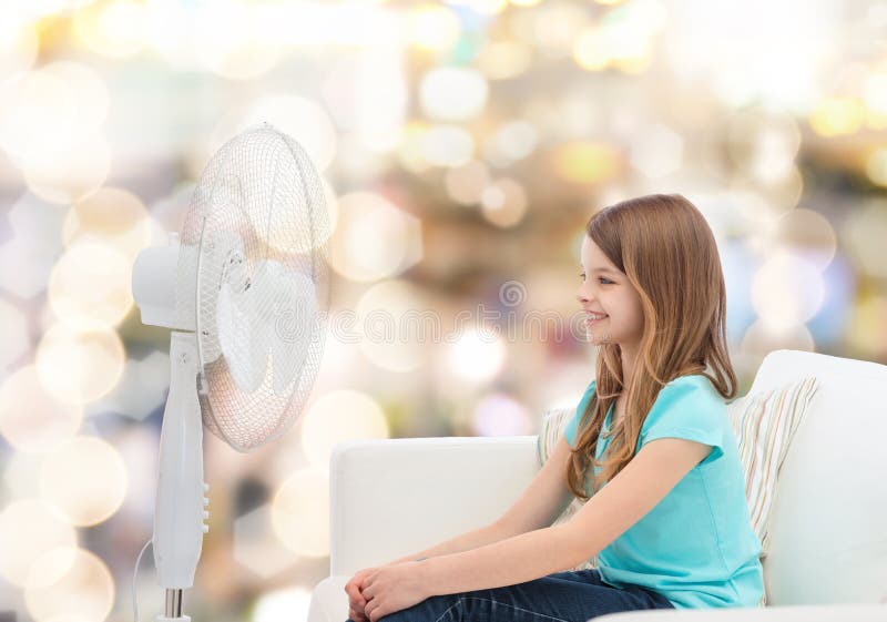 Smiling little girl with big fan at home