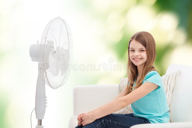 Smiling little girl with big fan at home