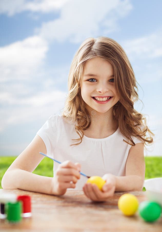 Smiling little girl coloring eggs for easter