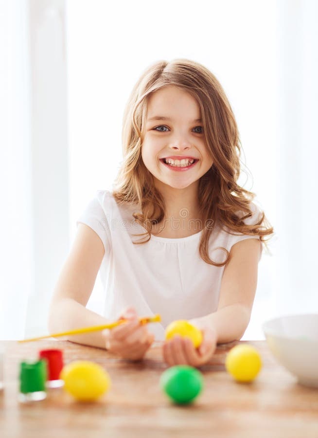 smiling little girl coloring eggs for easter