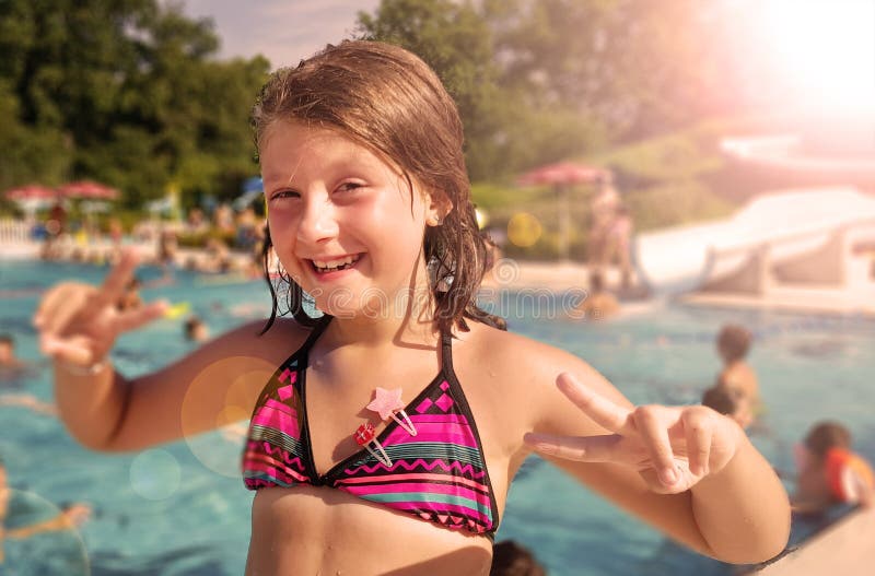 A smiling little girl is enjoying in the pool in a summer day