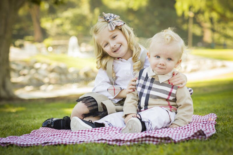 Smiling Little Girl Hugs Her Baby Brother at the Park