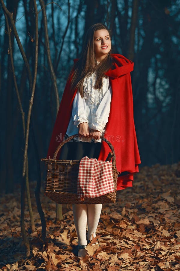 Smiling Little Red riding hood in the forest at night
