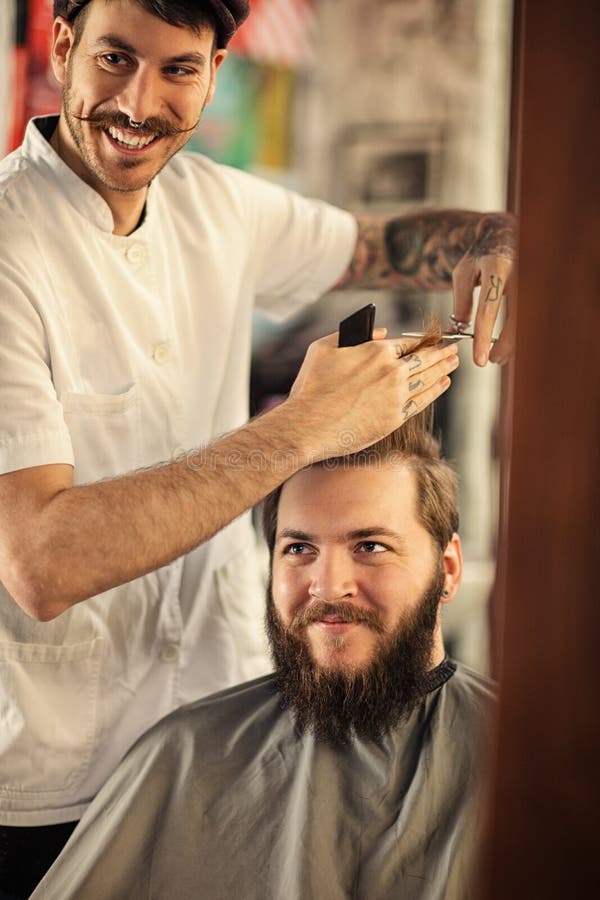 Smiling male barber giving client haircut royalty free stock photography Smiling male barber giving client haircut royalty free stock photography