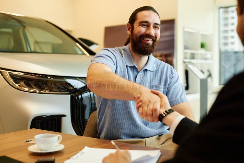 Smiling Male Buyer Shaking Hands with Auto Dealer at Dealership Center royalty free stock photos