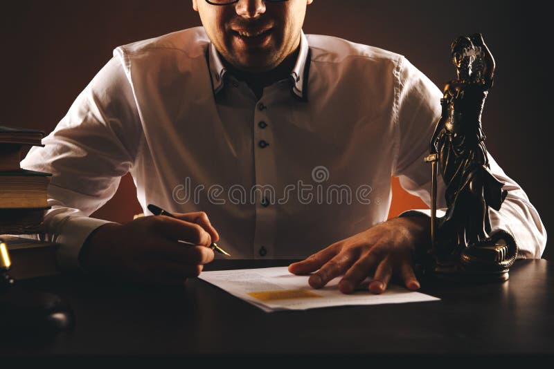 Smiling male lawyer on his desk with paperwork. Libra and wooden gavel and books. stock image Smiling male lawyer on his desk with paperwork. Libra and wooden gavel and books. stock image
