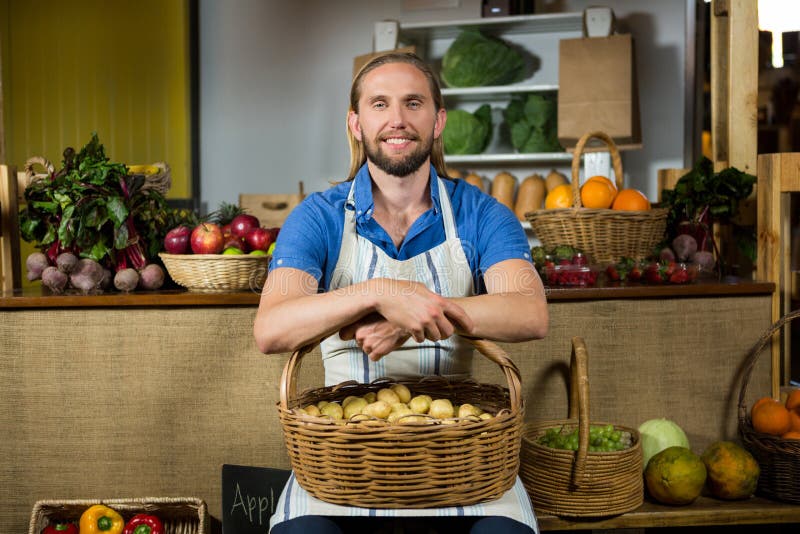 Smiling male staff siting with basket of potatoes at organic section stock photos Smiling male staff siting with basket of potatoes at organic section stock photos