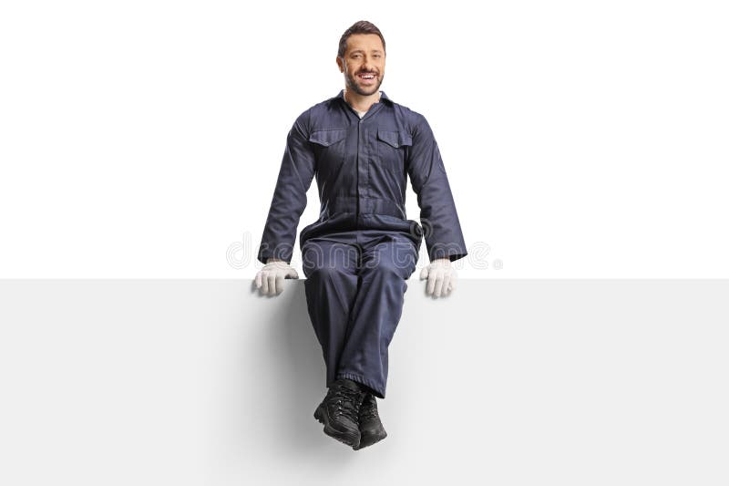Smiling male worker in a uniform and gloves sitting on a blank panel stock photos