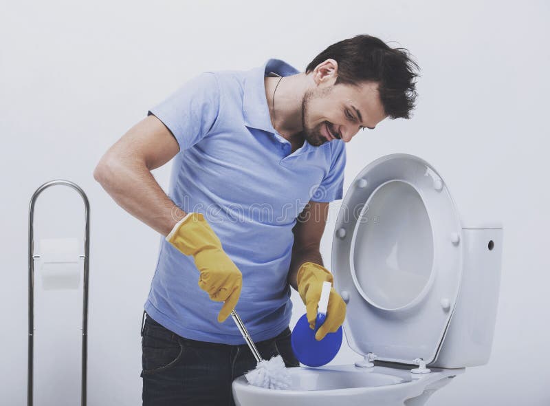Smiling man is cleaning toilet with brush. stock photo Smiling man is cleaning toilet with brush. stock photo