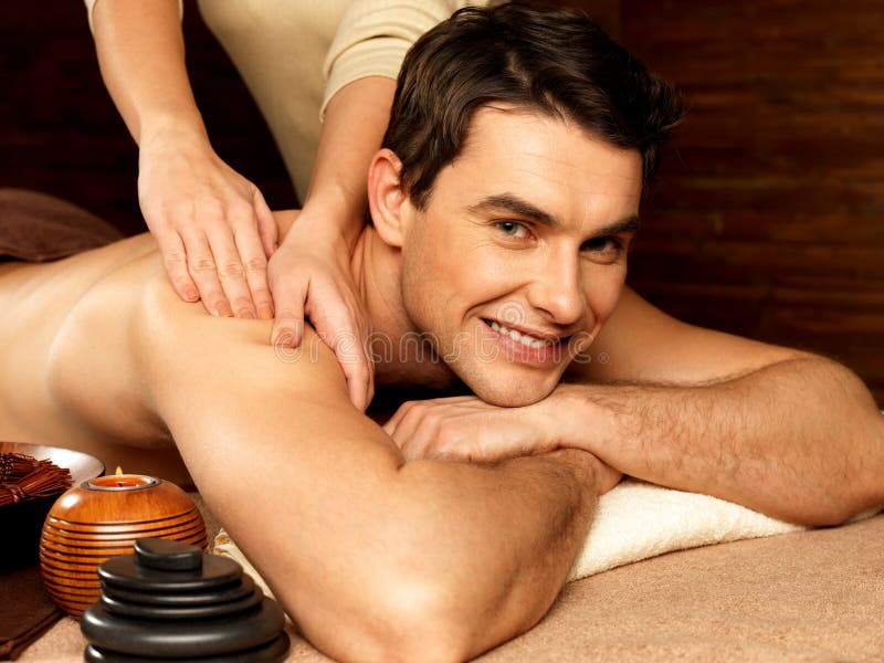 Smiling man having massage in the spa salon stock image