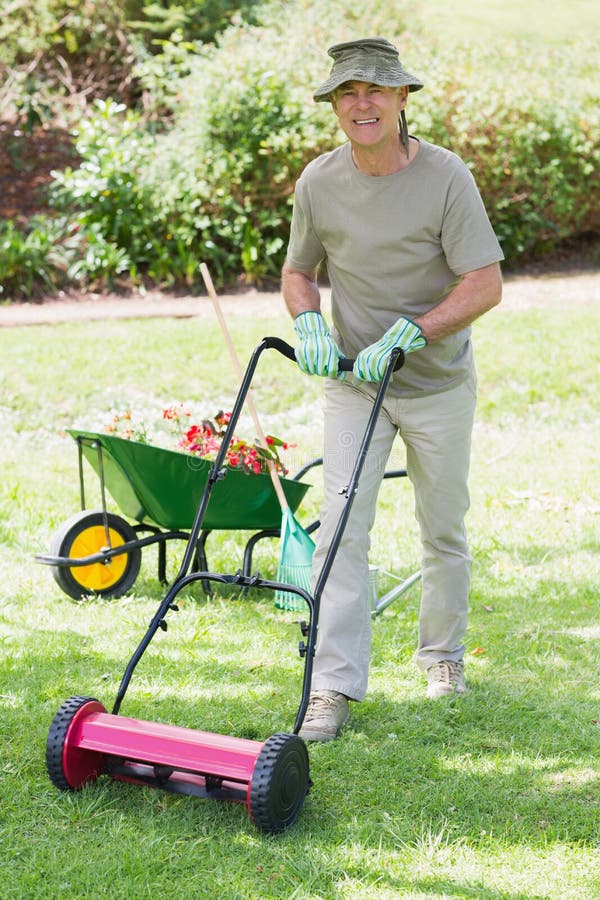 Smiling man mowing lawn stock image