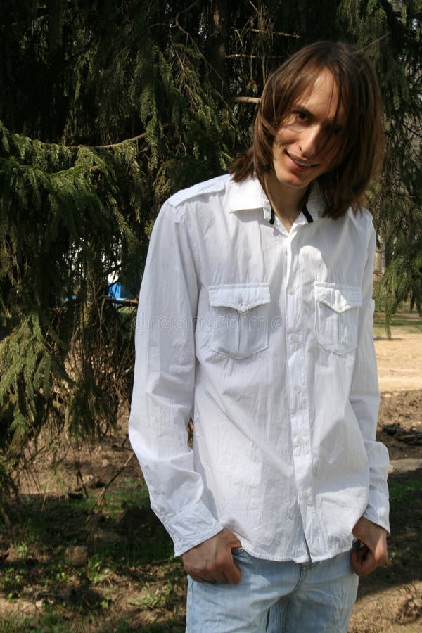 Smiling man standing under a fir tree