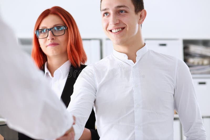 Smiling man in suit shake hands as hello in office