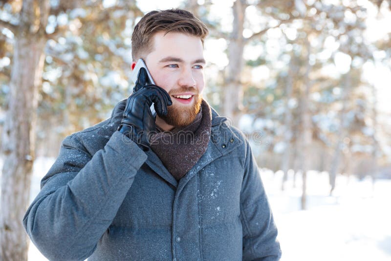 Smiling casual man talking on the phone in winter park