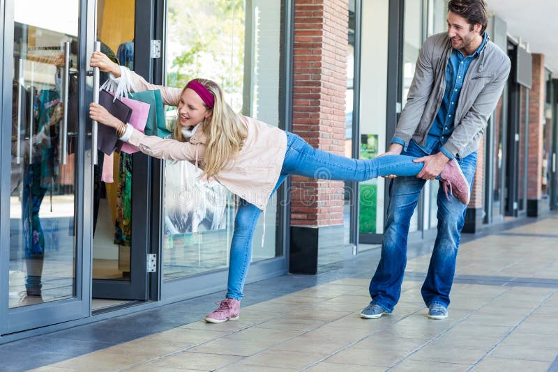 Шопингомания. Man straining to Pull away. Shopping Addiction. Pulling your Leg.