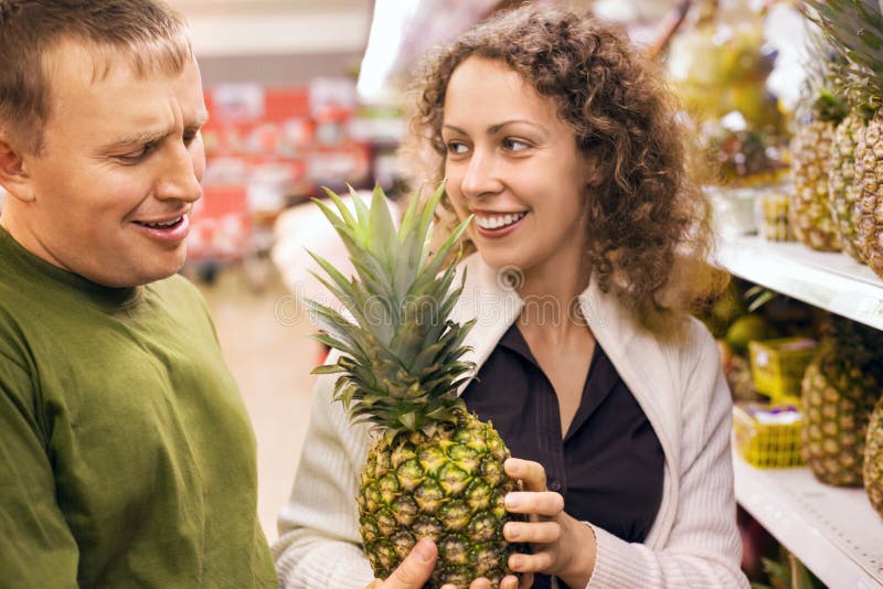 Smiling man and woman buy pineapple in supermarket stock photos Smiling man and woman buy pineapple in supermarket stock photos