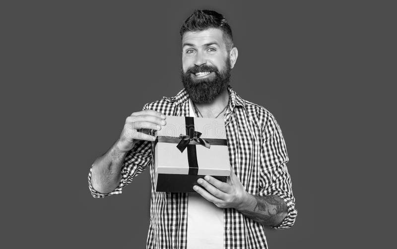 Smiling mature bearded man with present box on grey background stock image