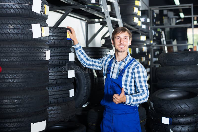 Smiling Mechanic Man Working with Car Tires in Stock Image
