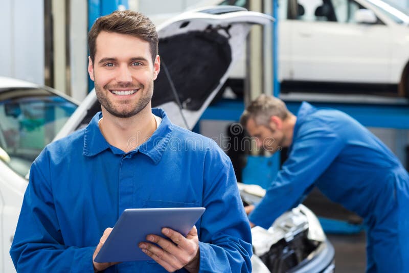 Smiling mechanic using a tablet pc stock photo