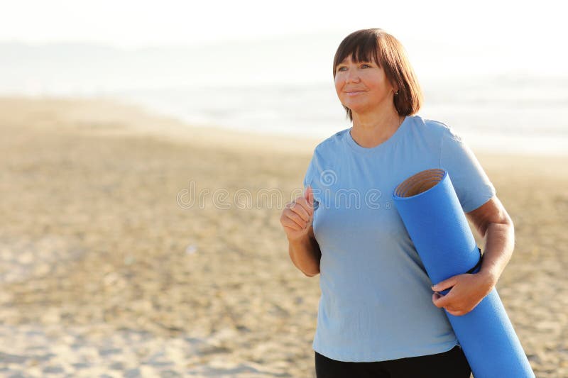 Smiling Middle Aged Woman Running On The Beach On Sunrise S Or S