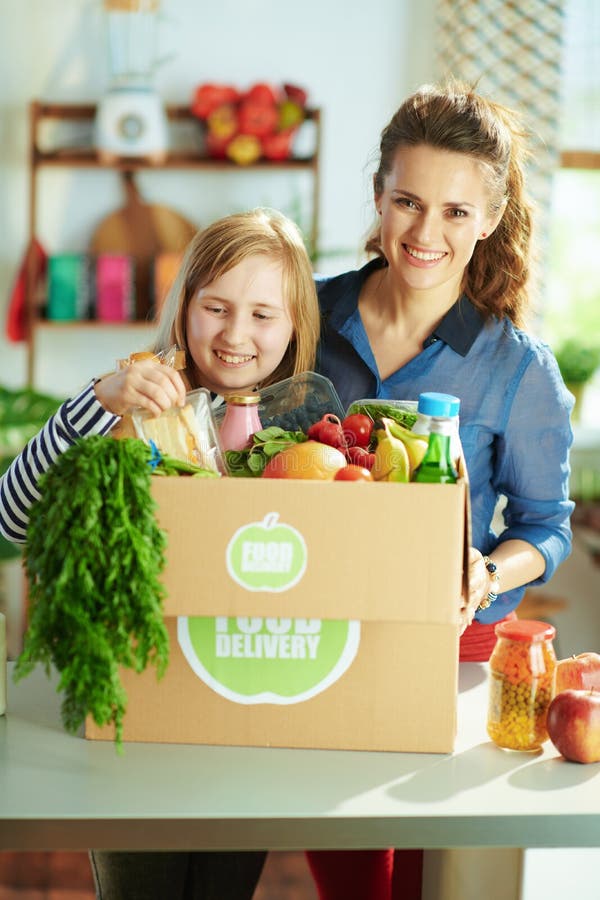 Smiling Modern Mother and Daughter with Food Box in Kitchen Stock Image