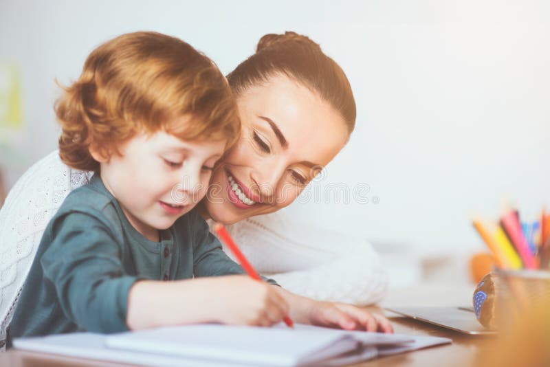 Smiling mother teaching her son to write stock image Smiling mother teaching her son to write stock image