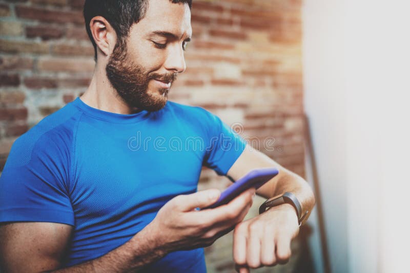 Smiling Muscular handsome athlete checking sport results on smartphone application and smart watch after good workout stock photo Smiling Muscular handsome athlete checking sport results on smartphone application and smart watch after good workout stock photo