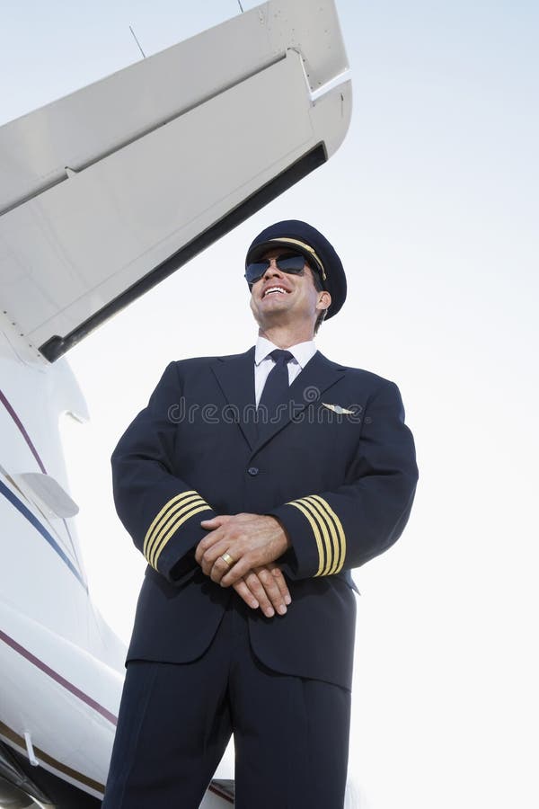 Smiling Pilot In Uniform Beside An Airplane stock image