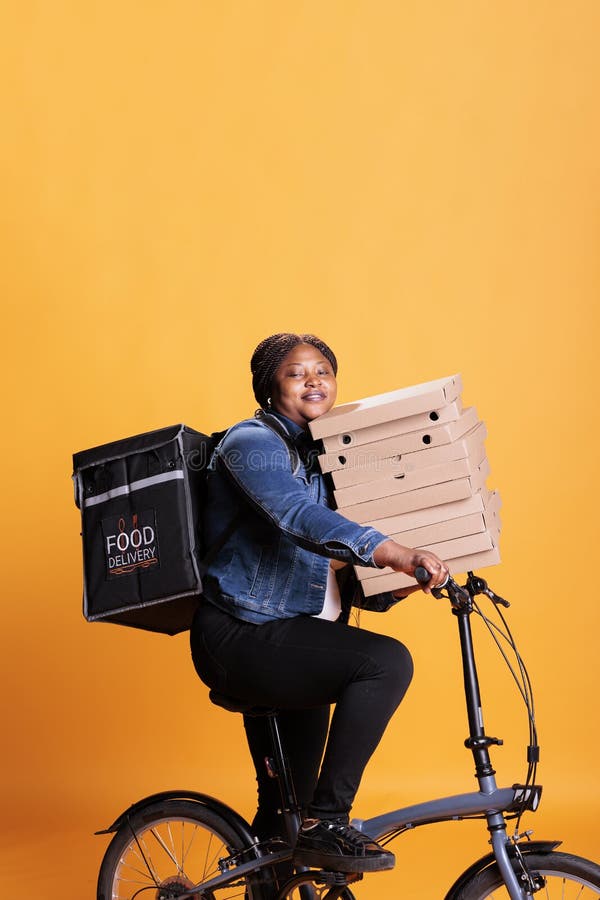 Smiling pizzeria delivery employee holding cardboard stack full with pizza delivering takeaway food order to client royalty free stock photo