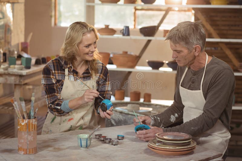 Smiling Potters Painting on Bowl in Pottery Stock Image
