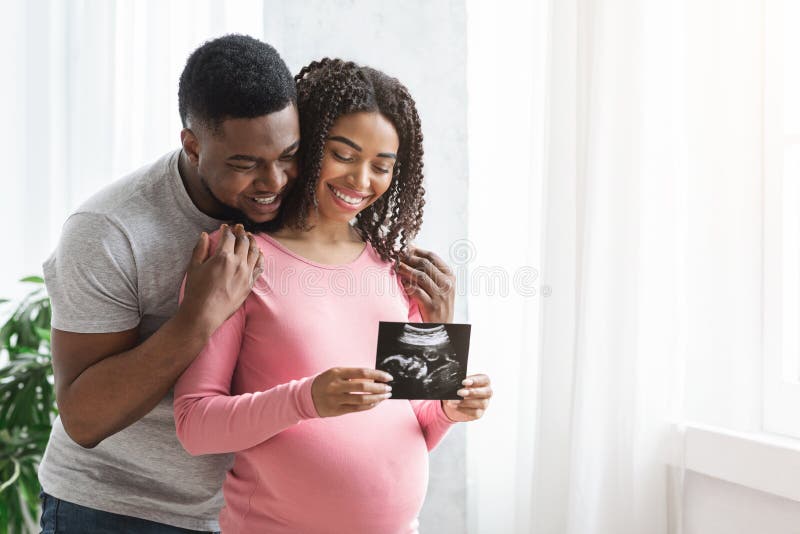 Smiling pregnant black couple showing ultrasound image of their baby stock images