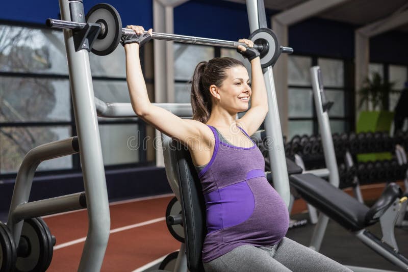 Smiling pregnant woman lifting barbell stock photography Smiling pregnant woman lifting barbell stock photography
