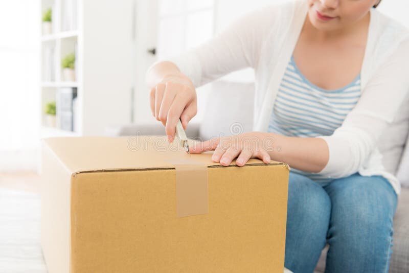 A Smiling Young Woman Opening Cardboard Box With A Box Cutter At Home  Delivered Gift By Air Mail Stock Photo, Picture and Royalty Free Image.  Image 101537170.