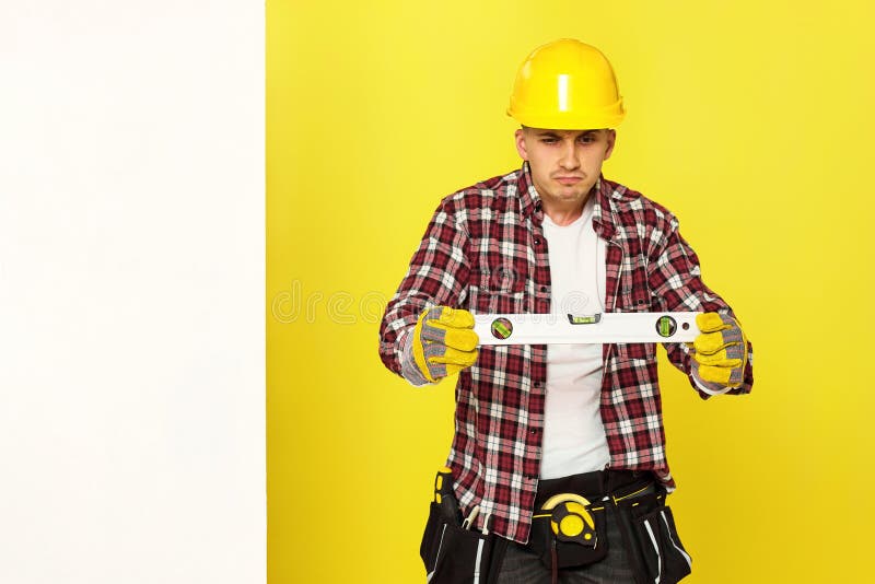 smiling professional builder in work clothes in helmet with level . royalty free stock photos