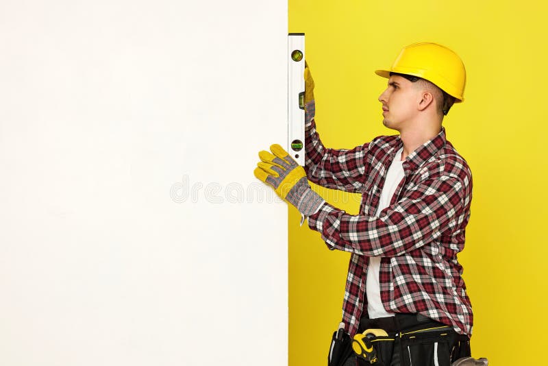 smiling professional builder in work clothes in helmet with level . stock image