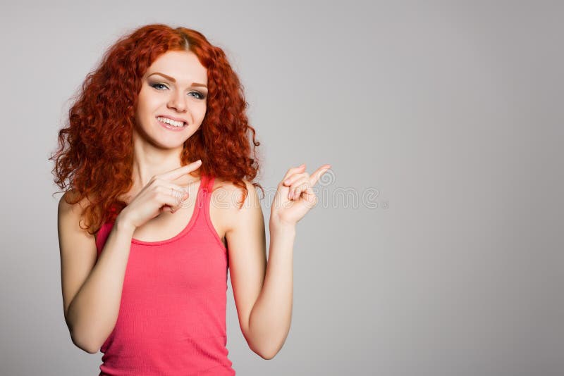 Smiling red haired girl is pointing fingers