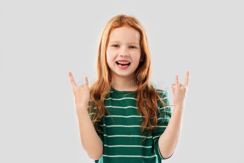 Smiling red haired girl showing rock gesture