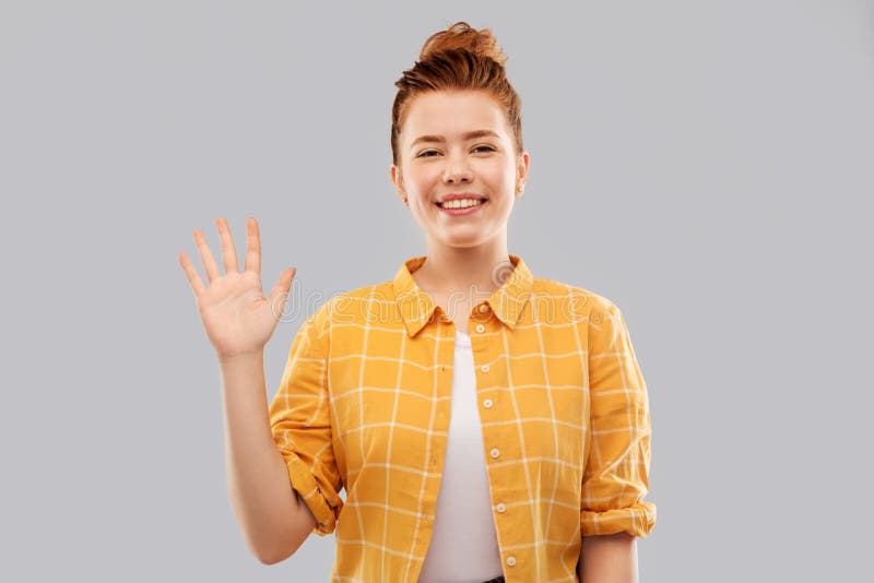 Smiling red haired teenage girl waving hand