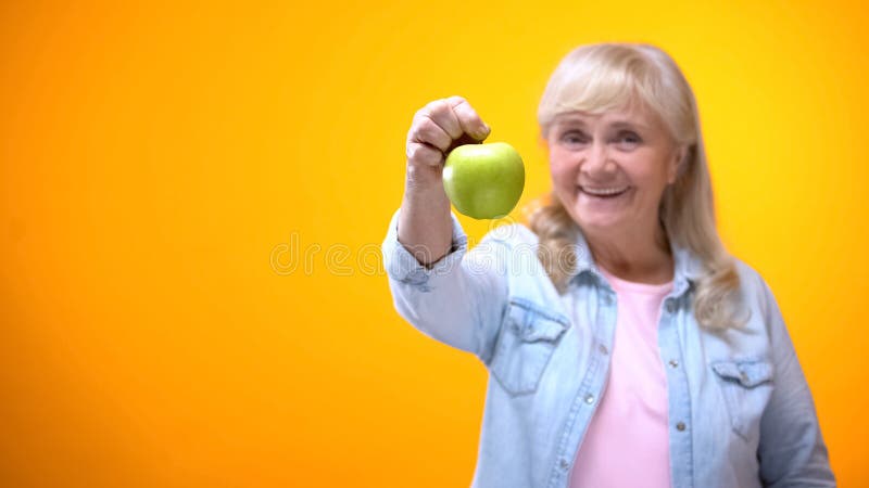 Smiling retiree vegetarian lady showing juicy green apple, organic food, dieting stock images Smiling retiree vegetarian lady showing juicy green apple, organic food, dieting stock images