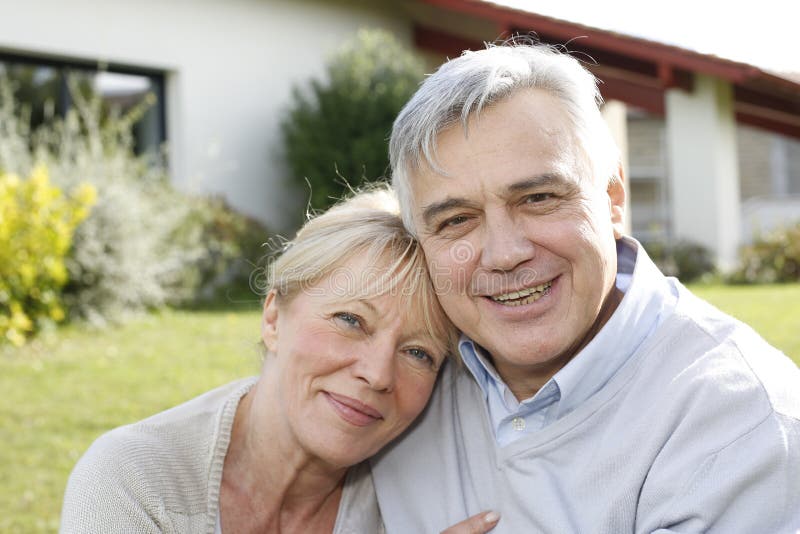 Smiling senior couple in front of their new house