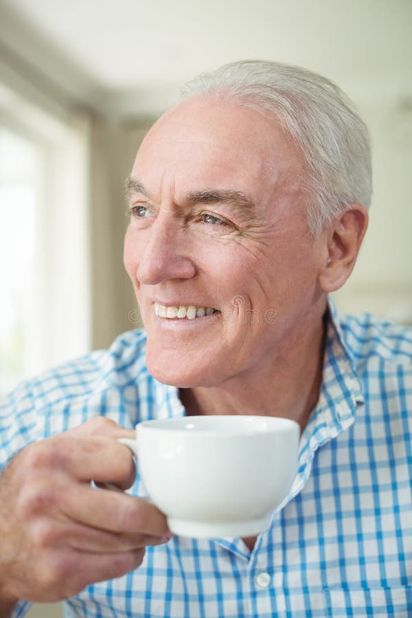 Smiling senior man having cup of coffee in living room royalty free stock photos Smiling senior man having cup of coffee in living room royalty free stock photos