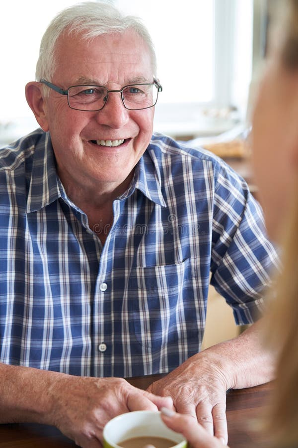 Smiling Senior Man Sitting In Kitchen Talking With Woman At Home royalty free stock photos Smiling Senior Man Sitting In Kitchen Talking With Woman At Home royalty free stock photos
