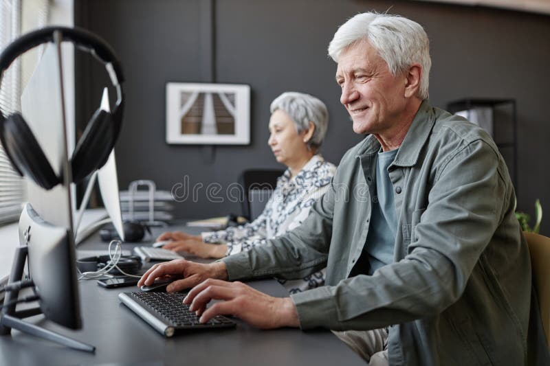 Smiling senior man using computer in class for elderly people royalty free stock image