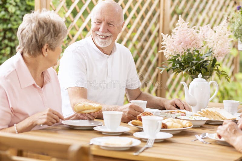 Smiling senior man eating breakfast with elderly woman on the te royalty free stock photos Smiling senior man eating breakfast with elderly woman on the te royalty free stock photos