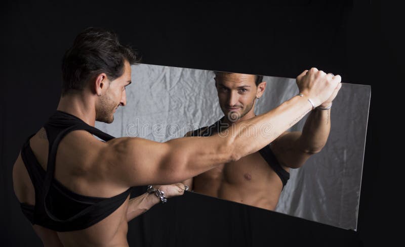 Smiling shirtless man holding mirror