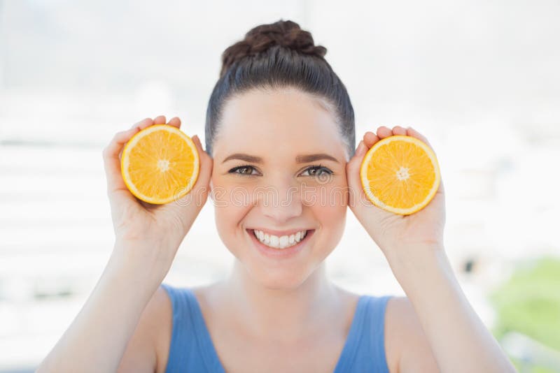 Smiling slender woman in sportswear holding slices of orange stock photography Smiling slender woman in sportswear holding slices of orange stock photography