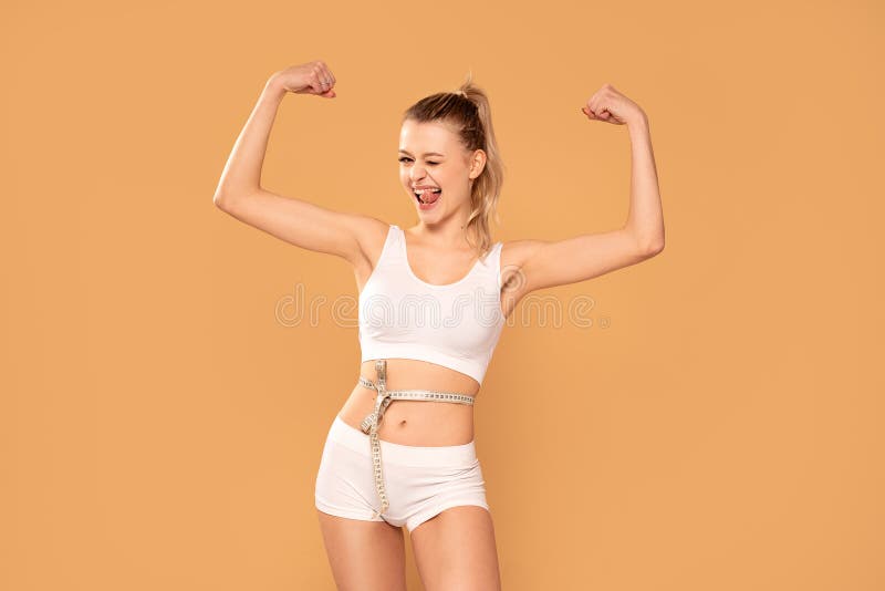 Smiling slim woman measuring her waist with tape .Fit young lady in perfect shape, happy with her body